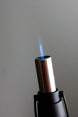 Close-up of a blue jet flame ignited from the extended nozzle of a red Eagle X-Pen refillable butane torch lighter, showcasing precise flame control.