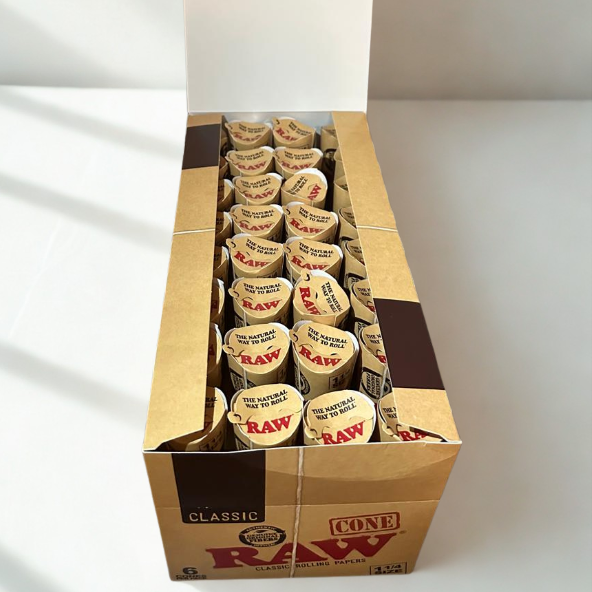 RAW Classic 1¼ Pre-Rolled Cones – Open Display Box Showing 32 Packs × 6 Cones, 100% Natural Unrefined Fibers.