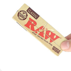 Hand holding one pack of RAW Classic Single Wide Rolling Papers – natural, unrefined, vegan paper